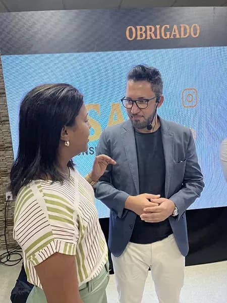 Amarildo Arruda conversando com uma participante diante do painel do evento